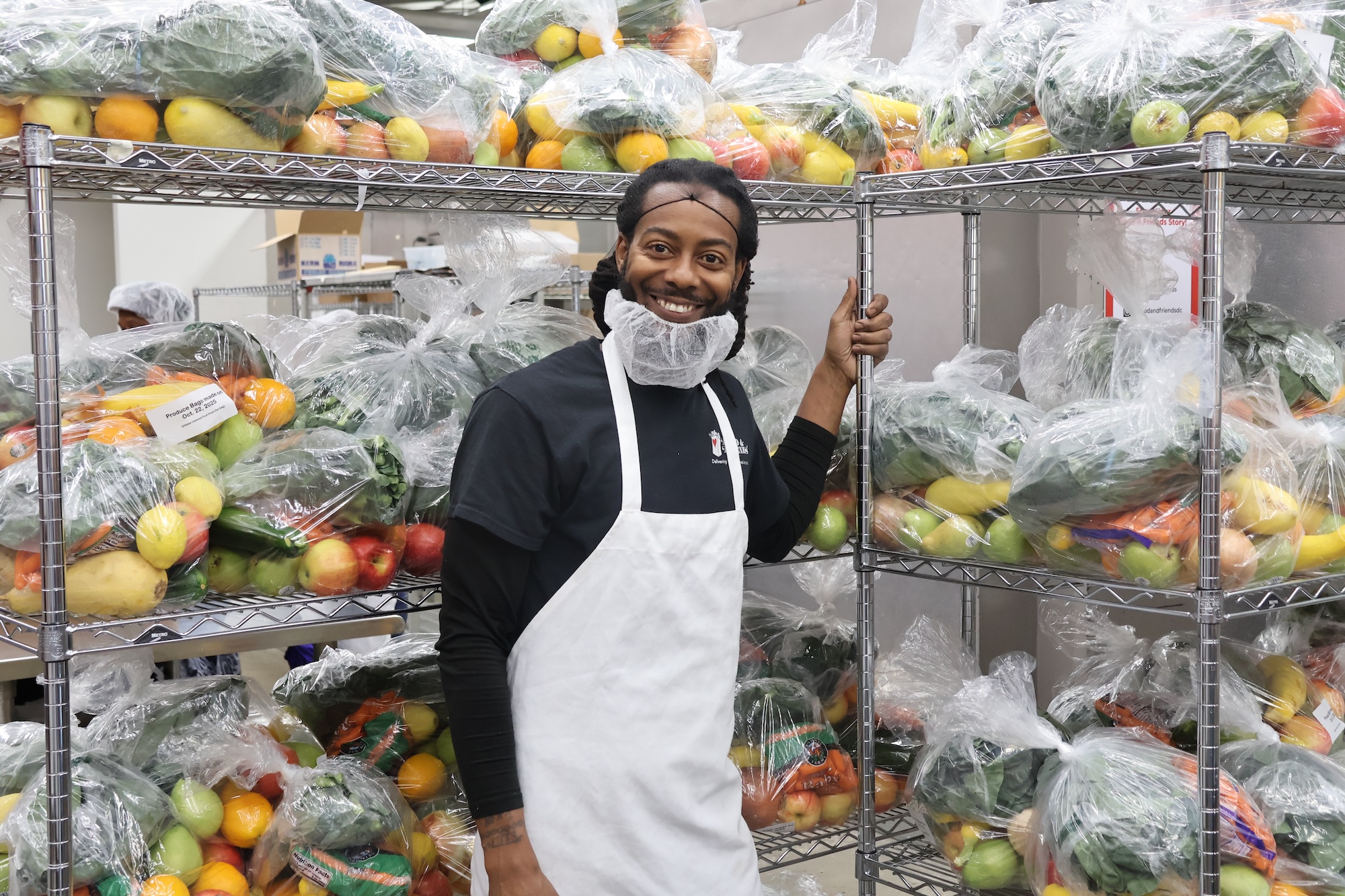 A staff member stands with the produce bags packed that day